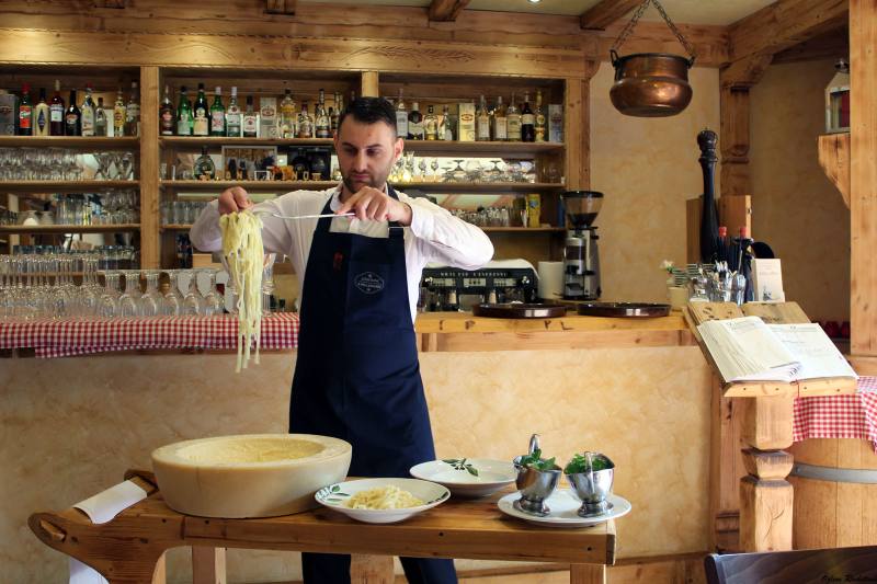 Pasta being flambéed in a wheel of cheese