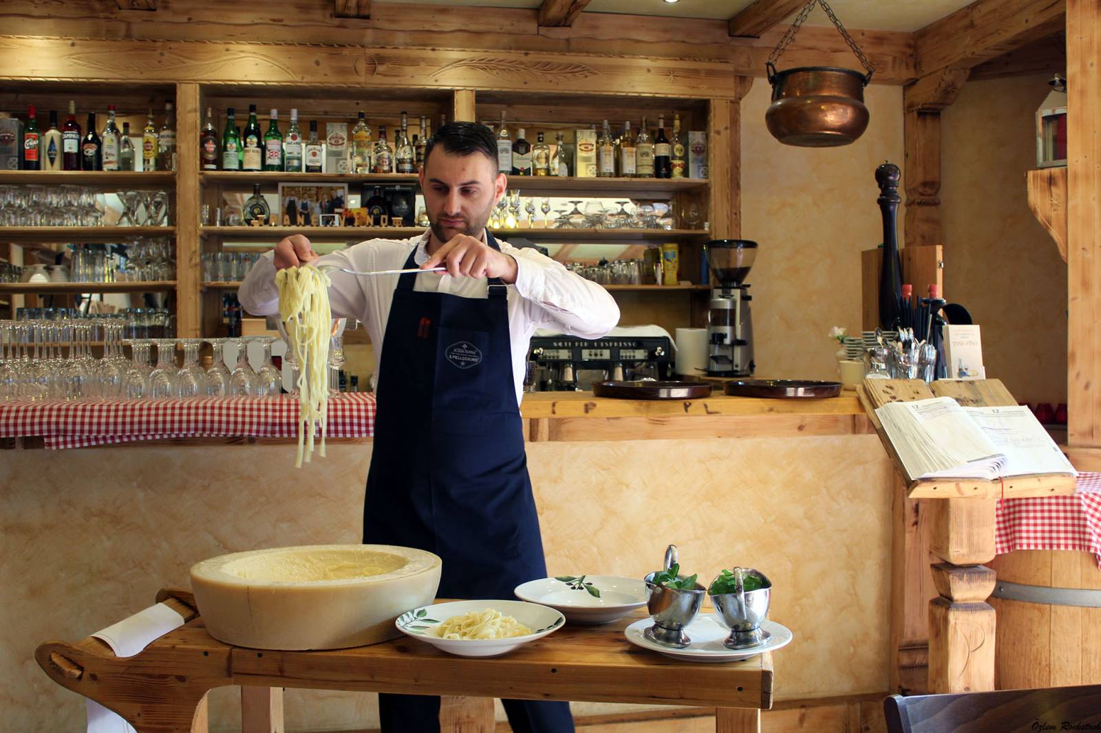 The chef tossing fresh pasta in a big wheel of cheese